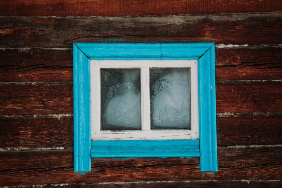 Close-up of a rustic wooden wall with a weathered blue-framed window.